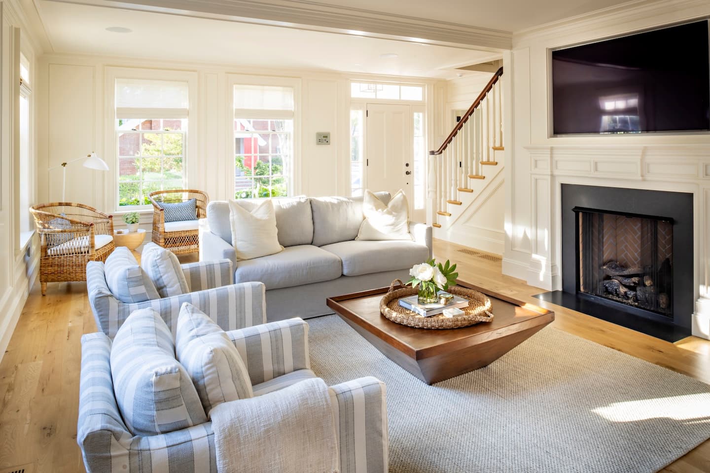 Living room with couches, fireplace, TV, stairs, and front door