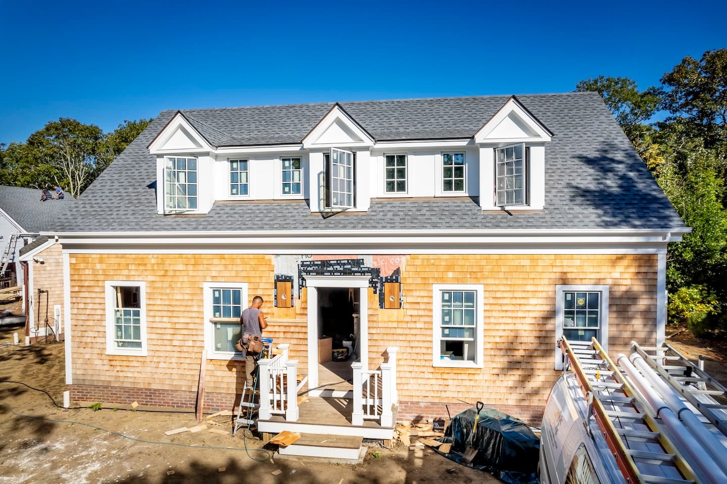 Construction worker installing shingles on the front of a new home